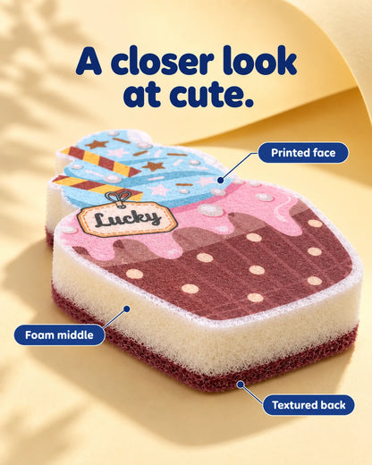 Angled close-up of the blue-and-brown cupcake sponge showing its printed face, cream foam middle and burgundy textured backing.