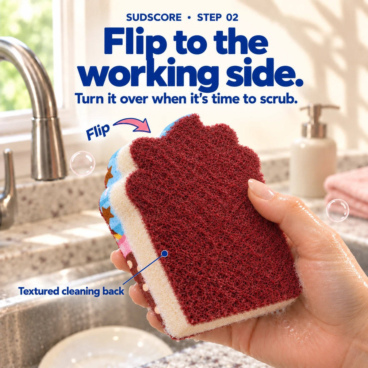 An adult hand turns the Blue & Brown Cupcake sponge to reveal its burgundy textured cleaning back and cream body.