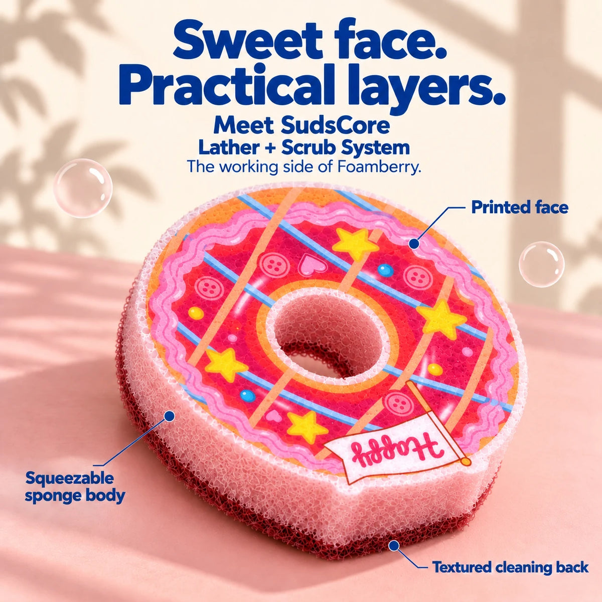 Pink Ring Donut showing its flat printed face, squeezable pink sponge body, and burgundy textured cleaning back.