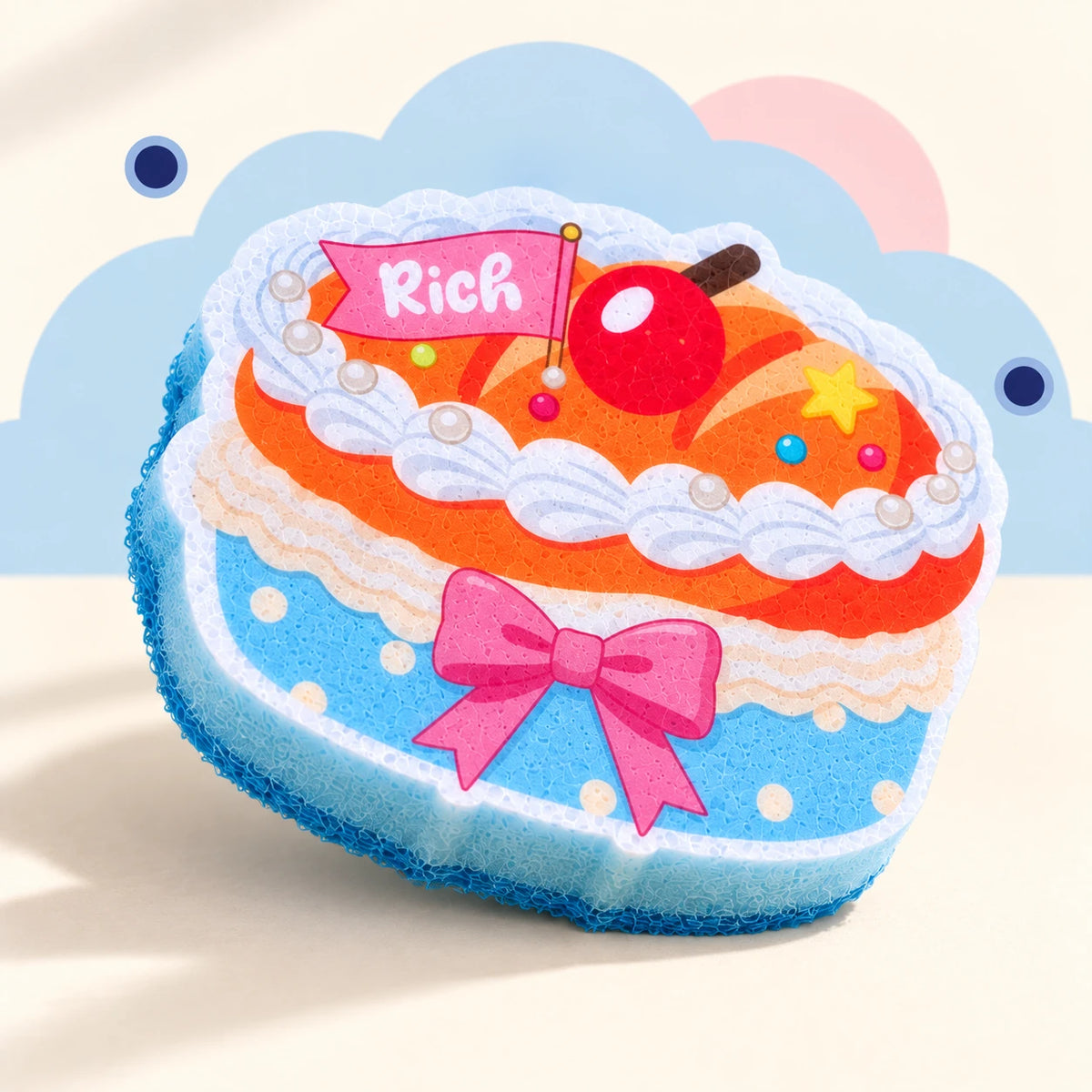 Round Layer Cake cleaning sponge with flat printed cherry and bow, blue dotted wrapper, and light-blue sponge body.