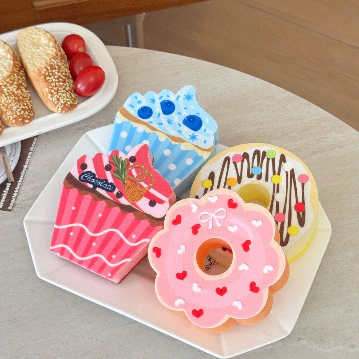 The actual four-piece set: pink heart donut, chocolate-style drizzle donut, pink cupcake and blue cupcake, arranged on a white plate.